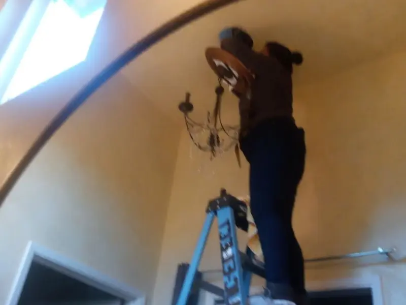 Electrician installing a chandelier in a Moxee residence